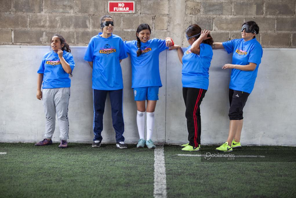 Cinco jugadoras de Topos Femenil durante el entrenamiento. Están recargadas sobre una de las paredes de la cancha mientras esperan el balón para jugar. 