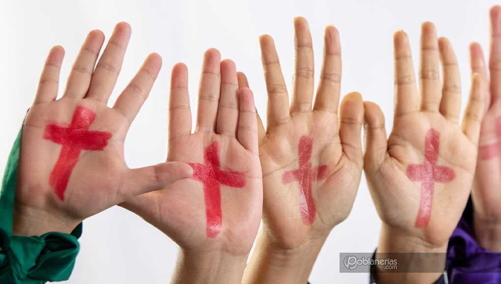 Cruces rosas en manos tema feminicidio